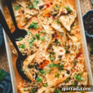 A baked Thai dumpling casserole in a white dish, filled with ramen noodles, dumplings, and a creamy curry sauce, garnished with scallions, cilantro, chili crisp, and sesame seeds.