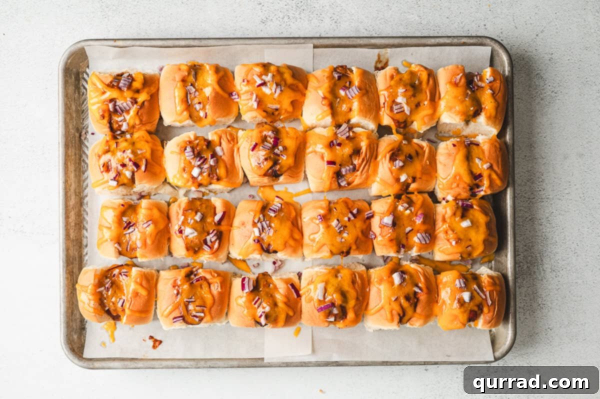 Bite-Sized Chili Cheese Dogs 6 Freshly baked mini chili cheese dogs straight from the oven, featuring perfectly melted cheddar and vibrant red onion atop the warm chili.