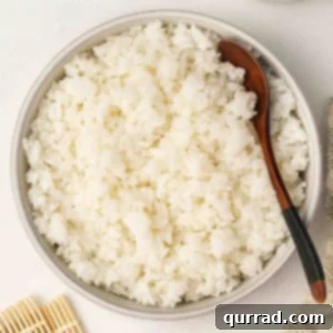 Secrets to Perfect Sushi Rice 3 Bowl filled with fluffy sushi rice and a wooden spoon, ready to use for rolls or bowls.