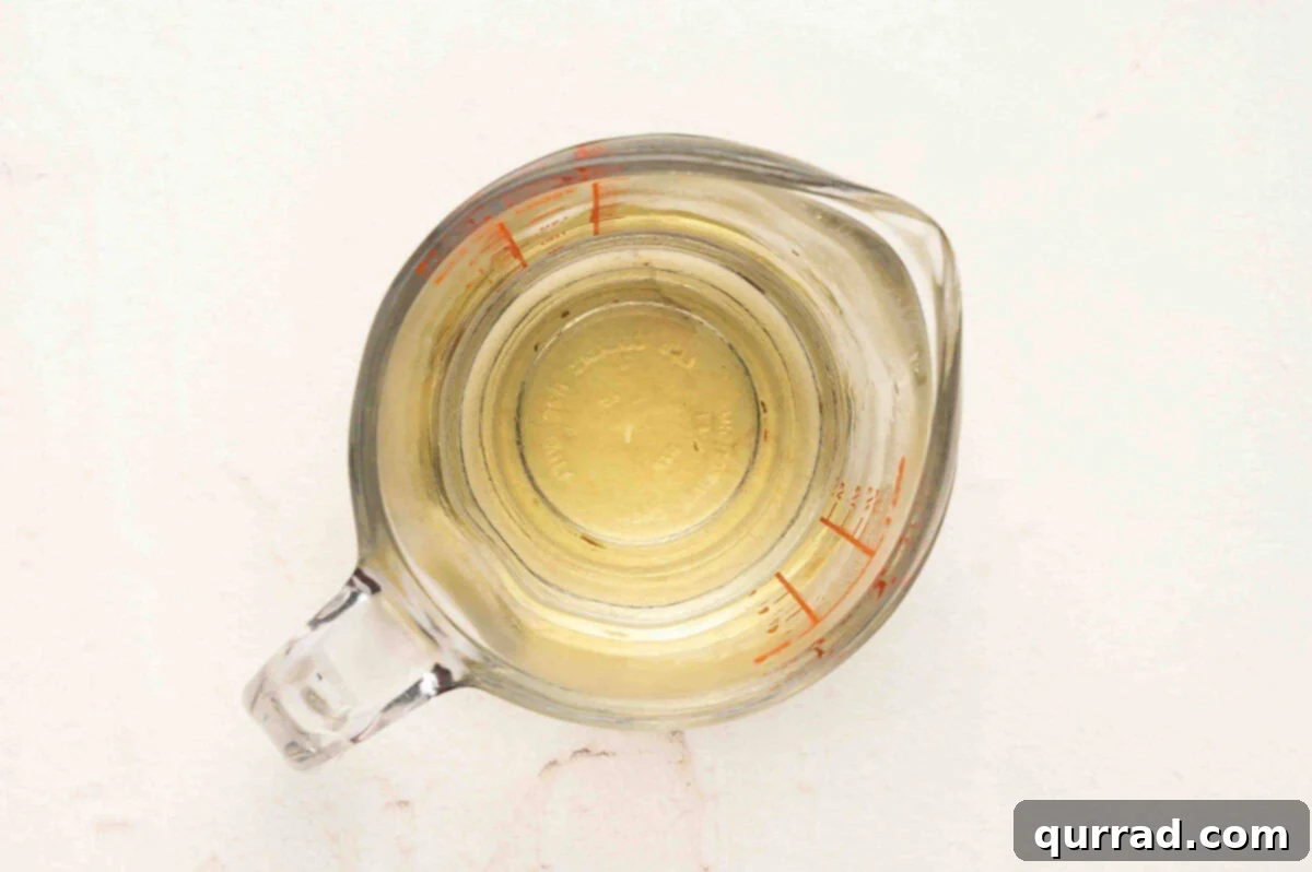 Secrets to Perfect Sushi Rice 6 Clear glass measuring cup with rice vinegar, sugar, and salt mixture for seasoning sushi rice.