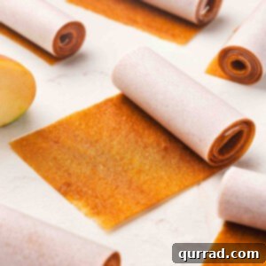 Rolled strips of homemade apple fruit leather wrapped in parchment paper, with one unrolled piece showing the chewy texture. Step 1: Bowl filled with peeled and chopped apples ready for cooking.