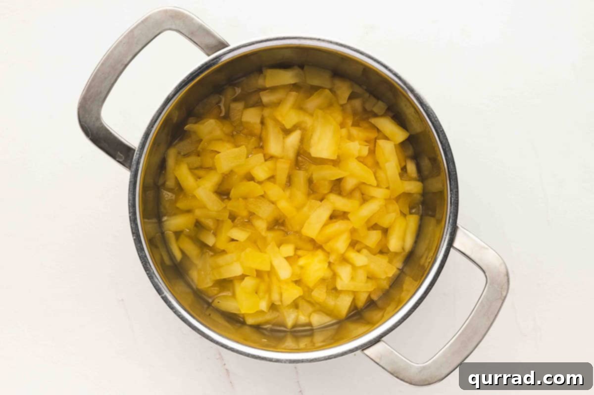 Pot of chopped apples simmering in water until softened.