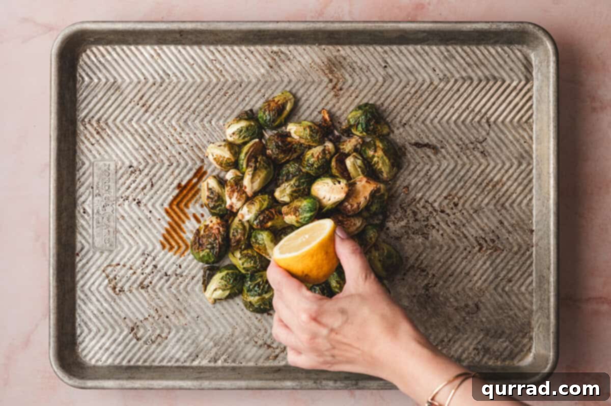 Balsamic Glazed Brussels Sprouts with Crispy Bacon 7 A hand squeezing lemon juice over roasted Brussels sprouts.