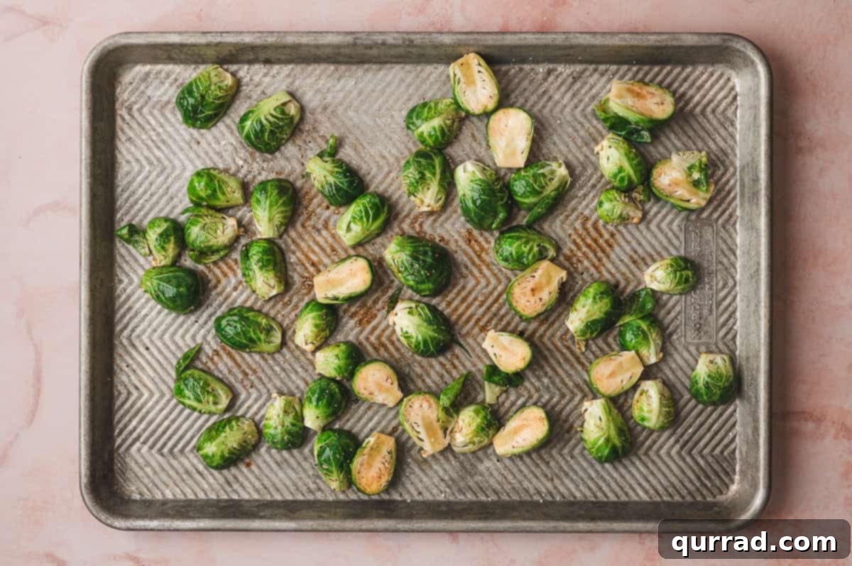 Balsamic Glazed Brussels Sprouts with Crispy Bacon 5 Seasoned Brussels sprouts spread in a single layer on a baking sheet.