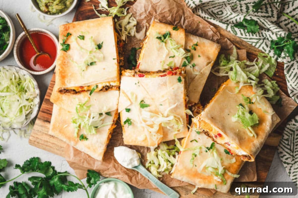 Overhead view of baked Crunchwrap Casserole cut into squares on a wooden board, topped with shredded lettuce and cilantro, surrounded by bowls of guacamole, sour cream, and hot sauce.