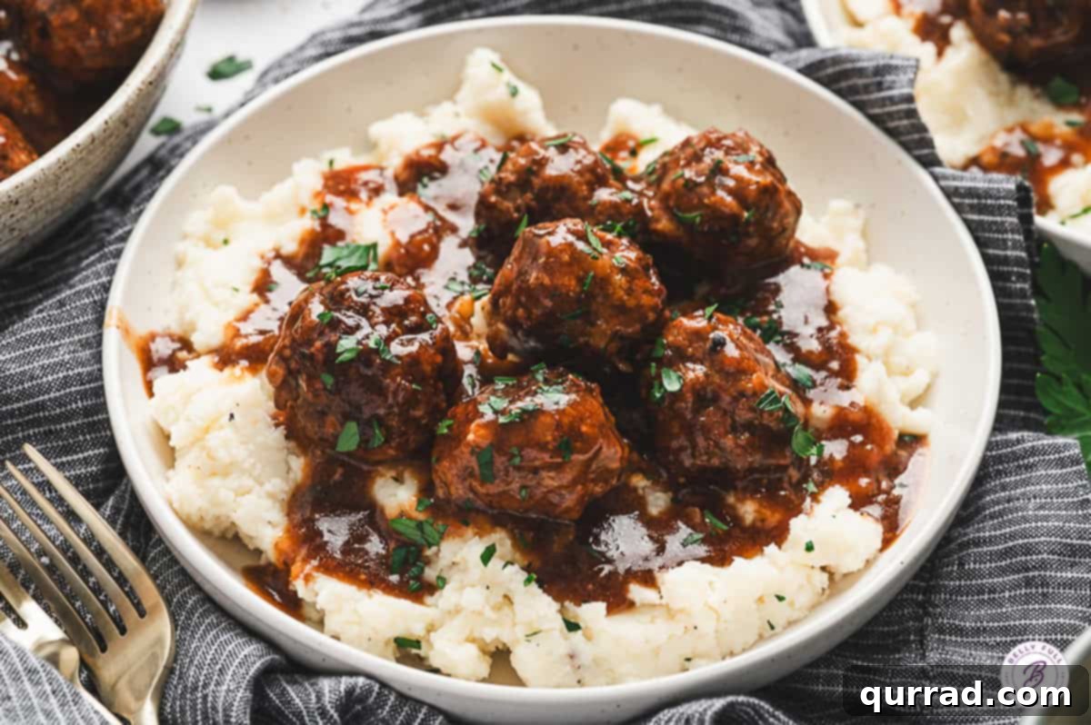 Savory Slow Cooker Salisbury Steak Meatballs 8 Plate of Salisbury steak meatballs served generously over mashed potatoes, topped with abundant rich gravy and a sprinkle of fresh parsley for garnish.