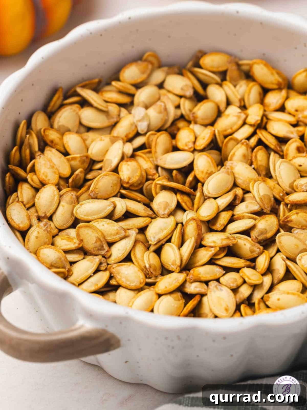 Bowl filled with golden roasted pumpkin seeds, lightly salted and ready for snacking, perfect for a healthy fall treat.