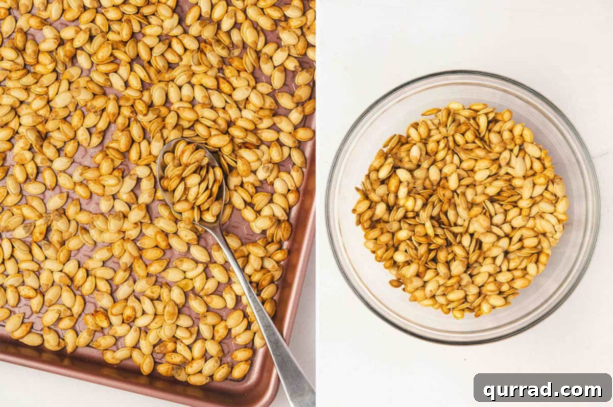 Freshly toasted pumpkin seeds being stirred on a baking sheet with a wooden spoon, showcasing their crisp and golden texture.