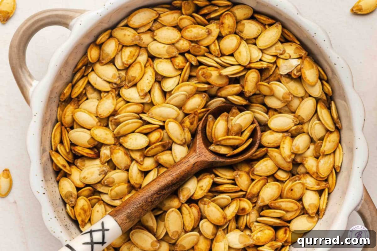 A white bowl filled with perfectly toasted roasted pumpkin seeds, accompanied by a small wooden spoon, inviting a delicious snack.