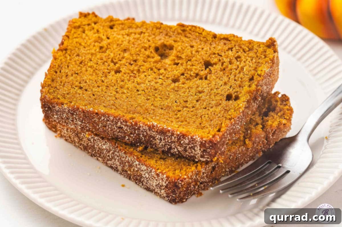 Two enticing slices of snickerdoodle pumpkin bread resting on a white plate with a fork, inviting a delicious bite.