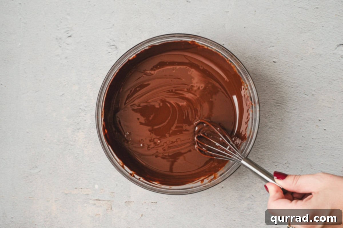 Decadent Dubai Truffles 8 Smooth melted dark chocolate in a glass bowl with a whisk.