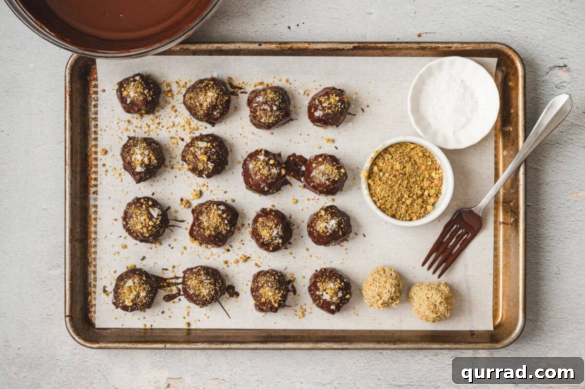 Decadent Dubai Truffles 10 Chocolate-coated truffles on a parchment-lined tray, sprinkled with crushed pistachios and sea salt.