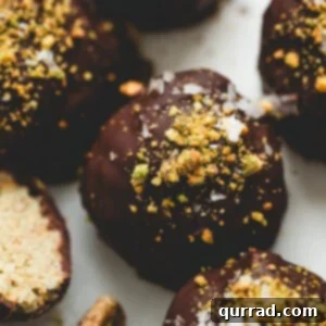 Decadent Dubai Truffles 3 Close-up of Dubai chocolate truffles coated in dark chocolate and topped with crushed pistachios and flaky sea salt, one truffle cut open to show the creamy pistachio kataifi filling.