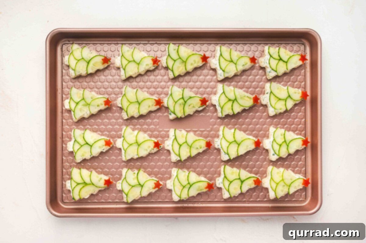 Christmas Tree Cucumber Bites 11 Rows of Christmas tree cucumber sandwiches arranged on a baking sheet, ready to serve