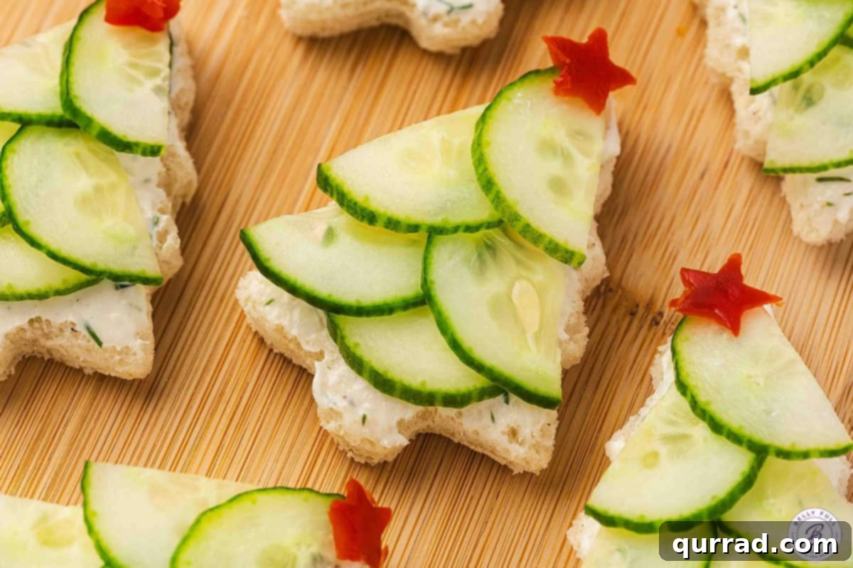 Christmas Tree Cucumber Bites 12 Close-up of festive Christmas tree cucumber sandwiches made with herbed cream cheese, layered cucumber slices, and red bell pepper stars on top