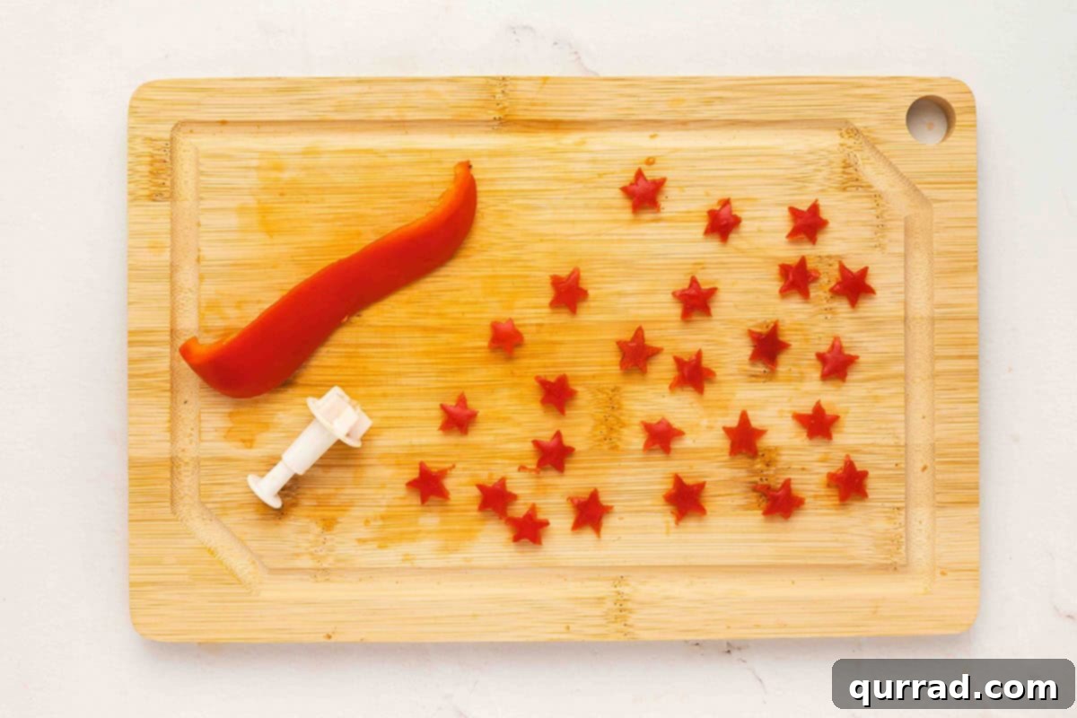 Christmas Tree Cucumber Bites 6 Small red bell pepper stars cut out with a mini star cutter on a wooden cutting board
