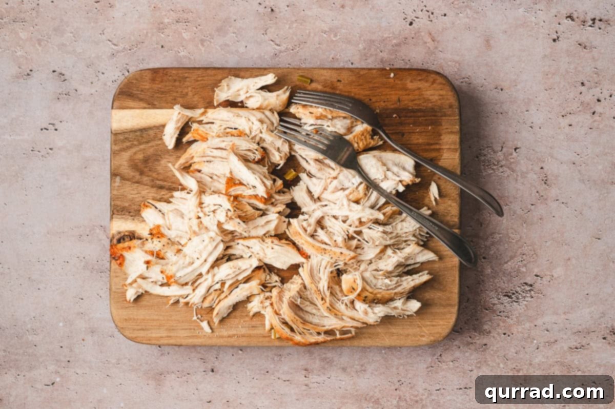Marry Me Chicken Comfort Soup 7 Shredding cooked chicken on a cutting board