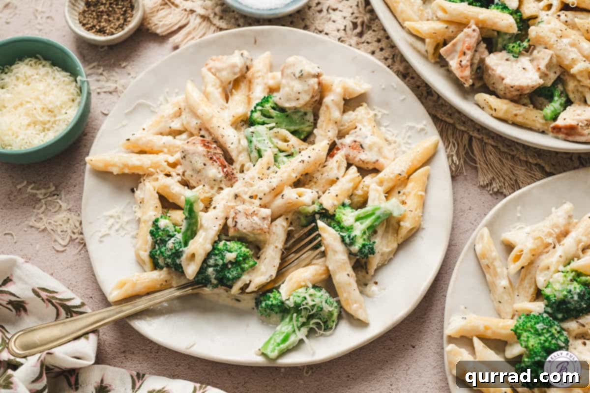 Plates of chicken broccoli alfredo garnished with Parmesan and black pepper, ready to serve.