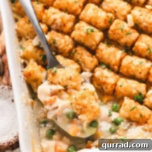 Chicken Tot Casserole 3 Overhead view of golden brown chicken tot pie baked in a white casserole dish, topped with rows of crispy tater tots.