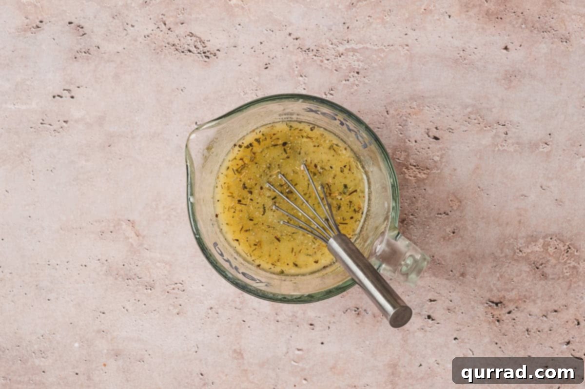 Garlic Bread Bites 4 Measuring cup filled with melted butter, garlic powder, Italian seasoning, and onion powder mixture with a whisk inside