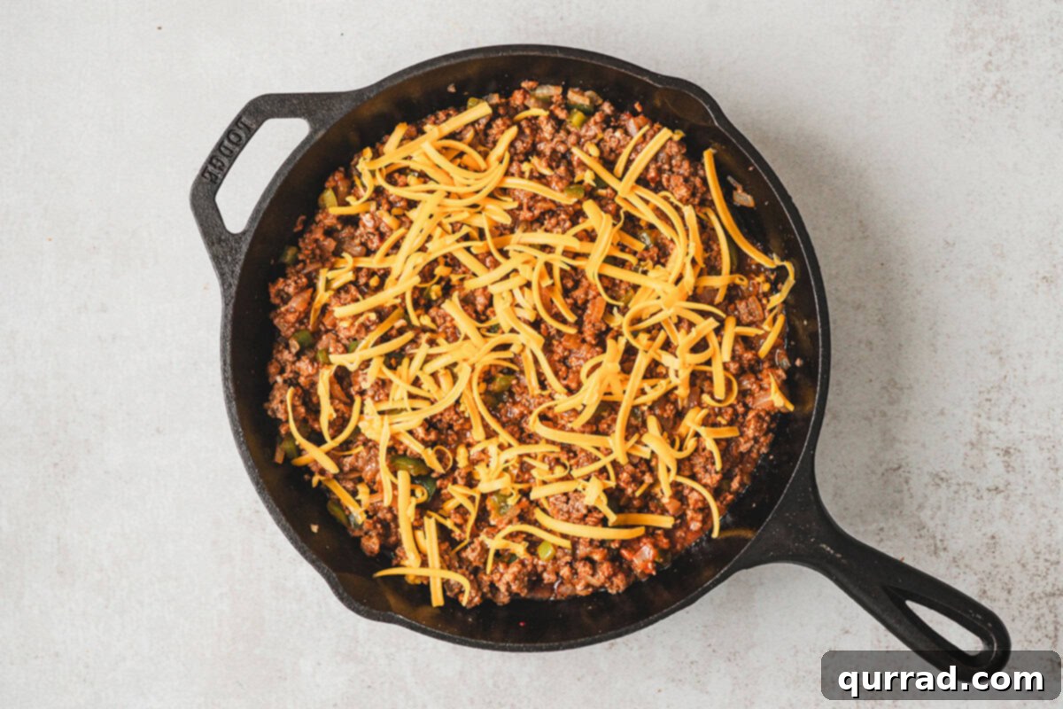 Shredded cheddar cheese sprinkled over the sloppy joe beef mixture.
