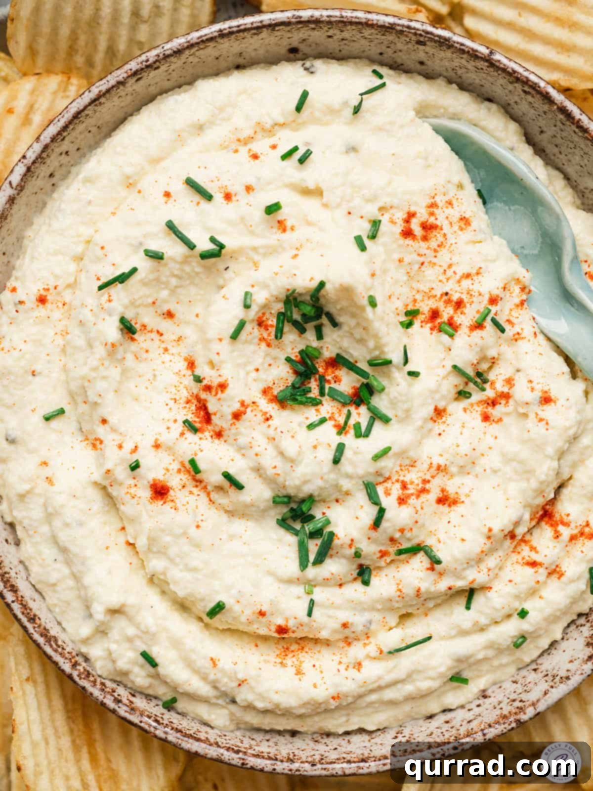 Deviled Egg Inspired Dip 2 Creamy deviled egg dip garnished with paprika and chopped chives, served in a bowl surrounded by ridged potato chips.