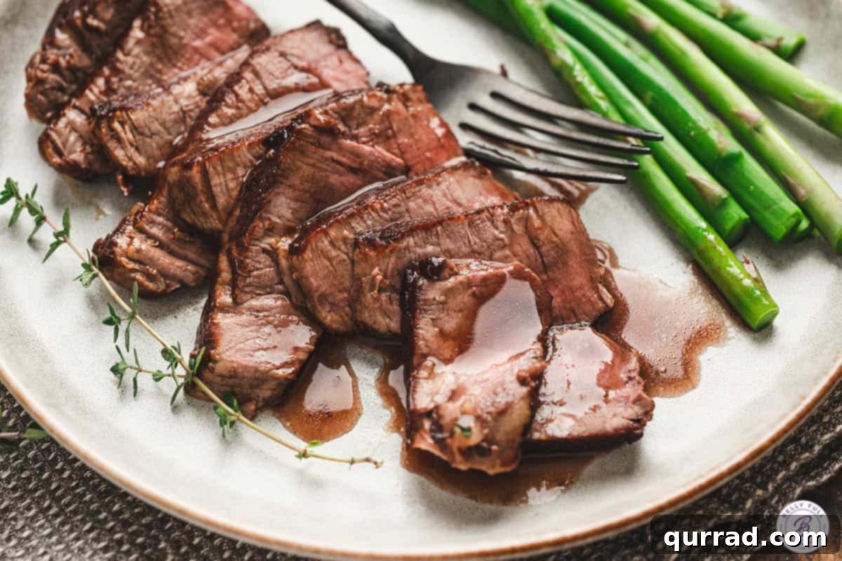 Velvety Red Wine Glaze 10 Close-up of sliced steak drizzled with homemade red wine sauce, served with fresh thyme and bright green asparagus.