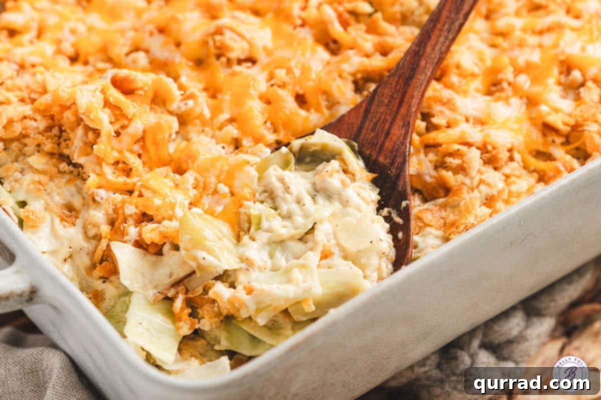 A wooden spoon scooping a generous portion of creamy cabbage casserole out of a baking dish, ready to be served.