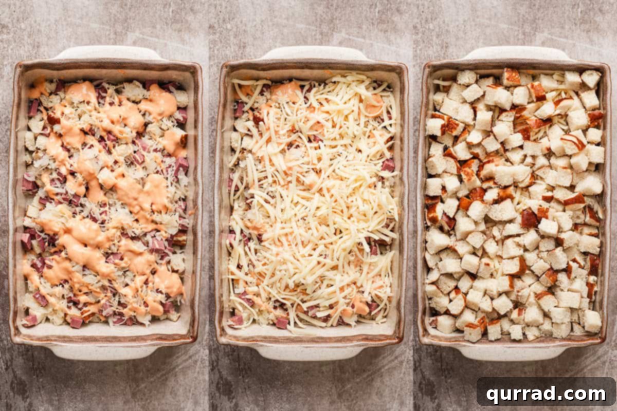 Reuben Sandwich Casserole 6 A baking dish showing the layers of diced pretzel buns, corned beef, sauerkraut, drizzled Thousand Island dressing, and shredded Swiss cheese, ready for the final bread layer.