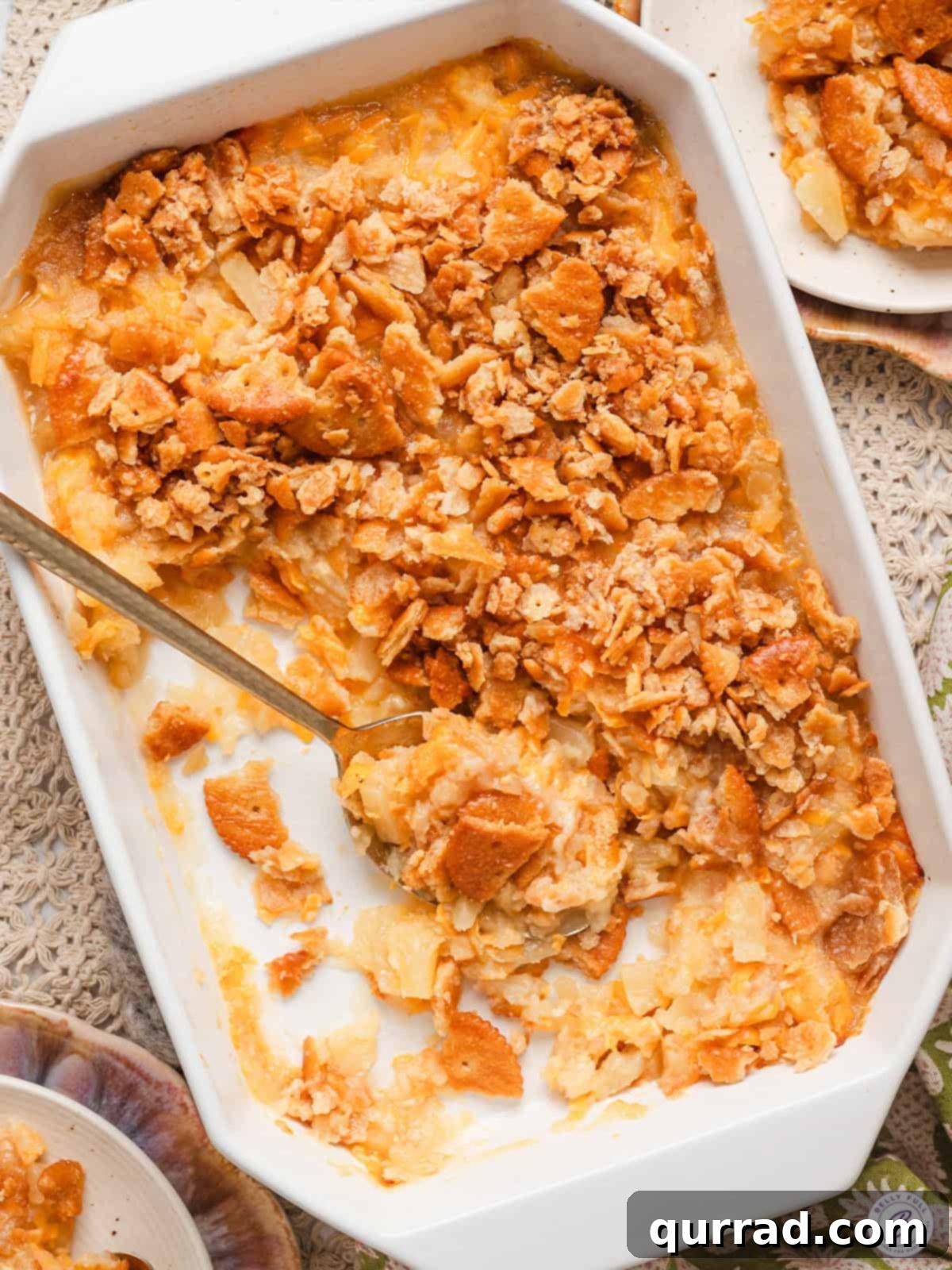 Overhead view of a southern pineapple casserole in a baking dish with a spoon and some of the casserole removed.