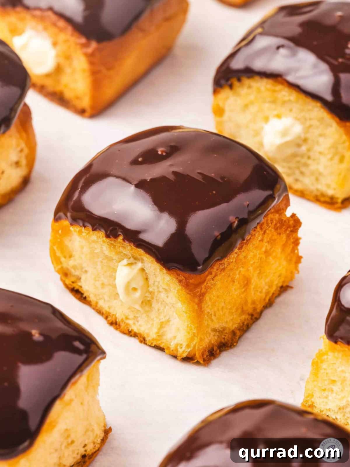Boston Cream Pie Swirl Donuts 2 Side view of Boston Cream Pie Roll “Donuts” showcasing the golden roll, creamy filling, and chocolate glaze.