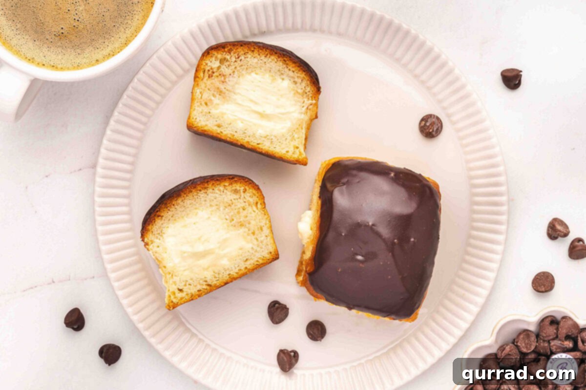 Boston Cream Pie Swirl Donuts 12 Overhead view of two Boston cream roll pie 'donuts' on a plate, with one cut open to reveal the creamy vanilla filling.