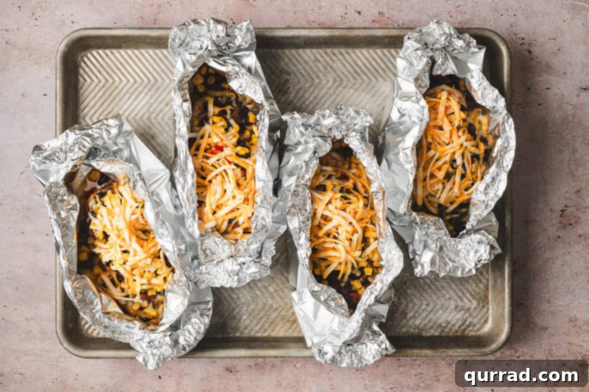 Four Southwestern Chicken Foil Packets on a baking sheet, now with melted cheese added for extra deliciousness.