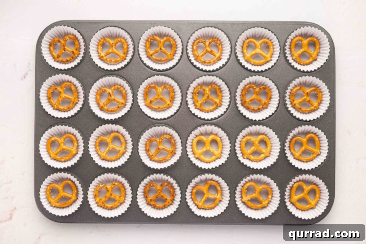 Mini pretzels placed in mini paper liners within a muffin tin.