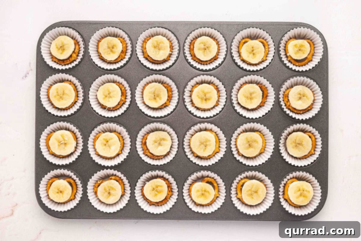 Banana slices placed on top of pretzels in mini muffin liners.