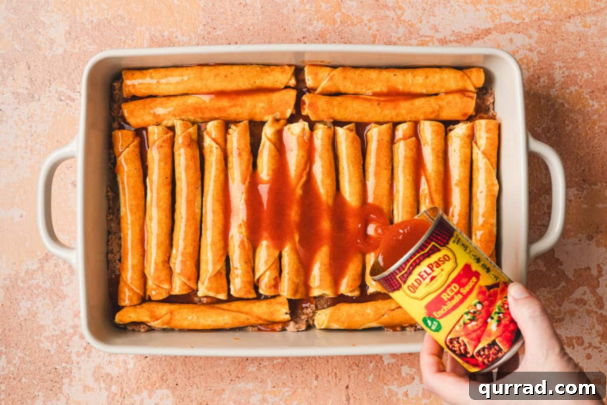 Effortless Enchilada Bake 8 Enchilada sauce being poured generously over the layer of frozen taquitos in the baking dish.