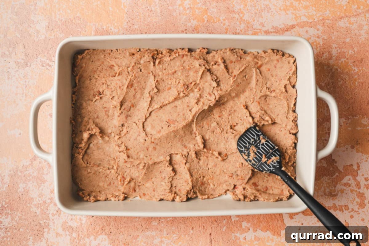 Effortless Enchilada Bake 6 The seasoned refried bean mixture spread evenly across the bottom of a 13x9 inch baking dish.