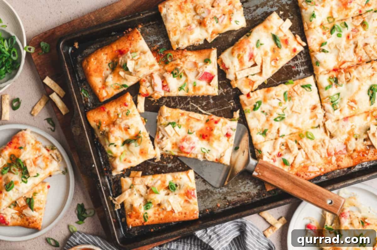 Crab Rangoon Pizza Delight 8 Crab rangoon pizza cut into squares on a sheet pan, topped with scallions and crispy wonton strips.