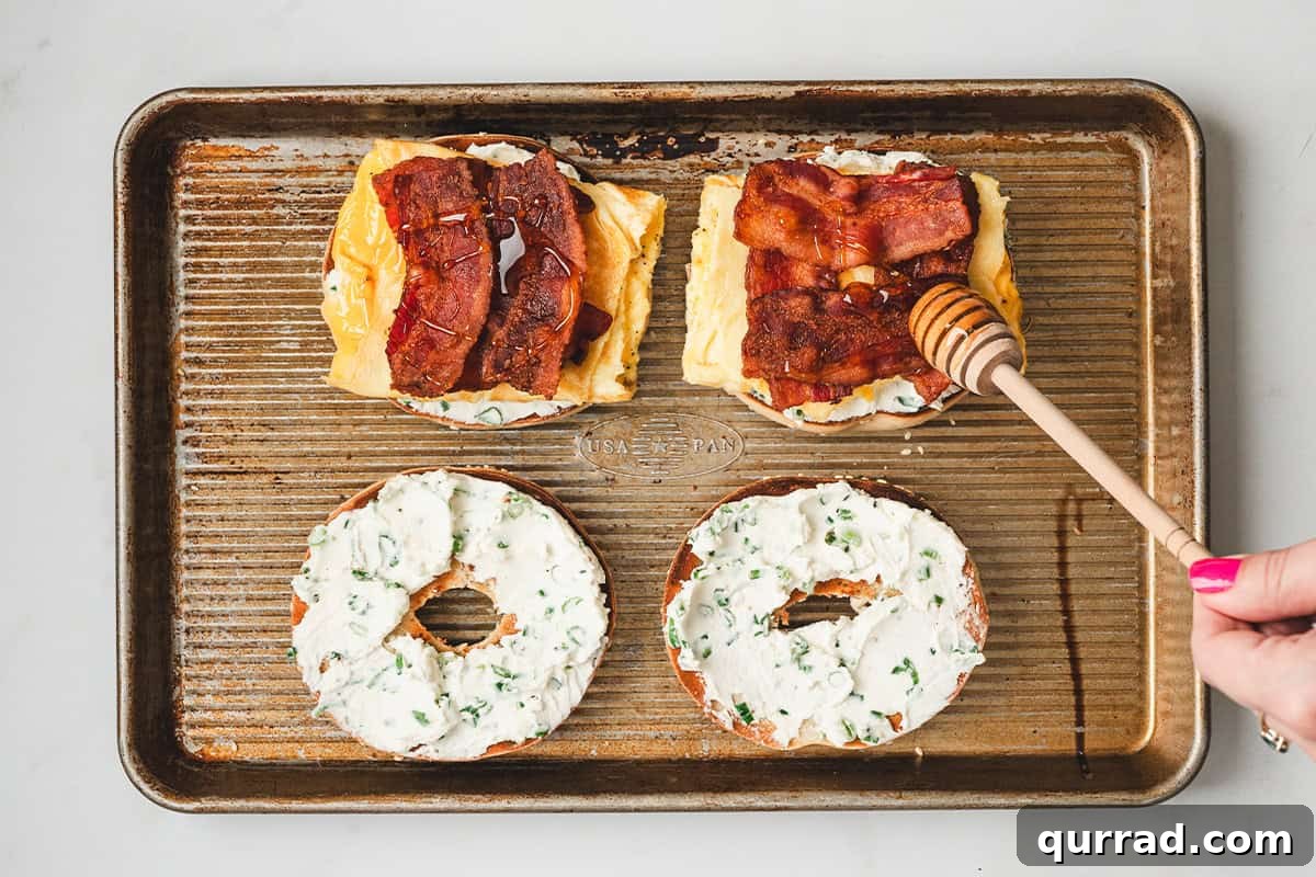 Drizzling hot honey over bacon and eggs on an open-faced bee sting bagel