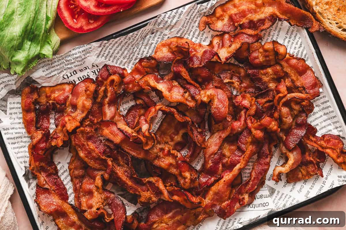 Crispy cooked bacon strips cooling on a parchment-lined baking sheet