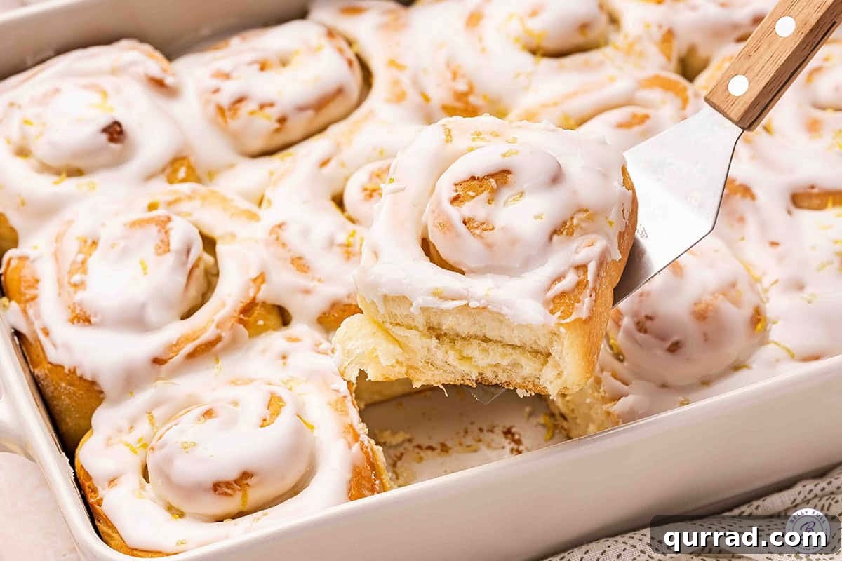 A lemon sweet roll being lifted out the pan.