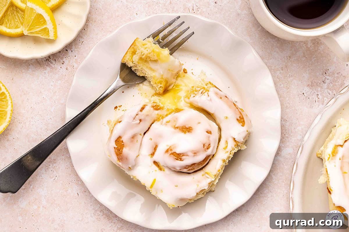 Overview of a lemon roll on a plate with a piece missing.