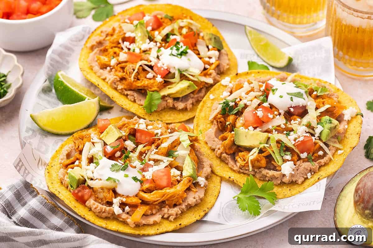 Three chicken tinga tostadas on a plate.