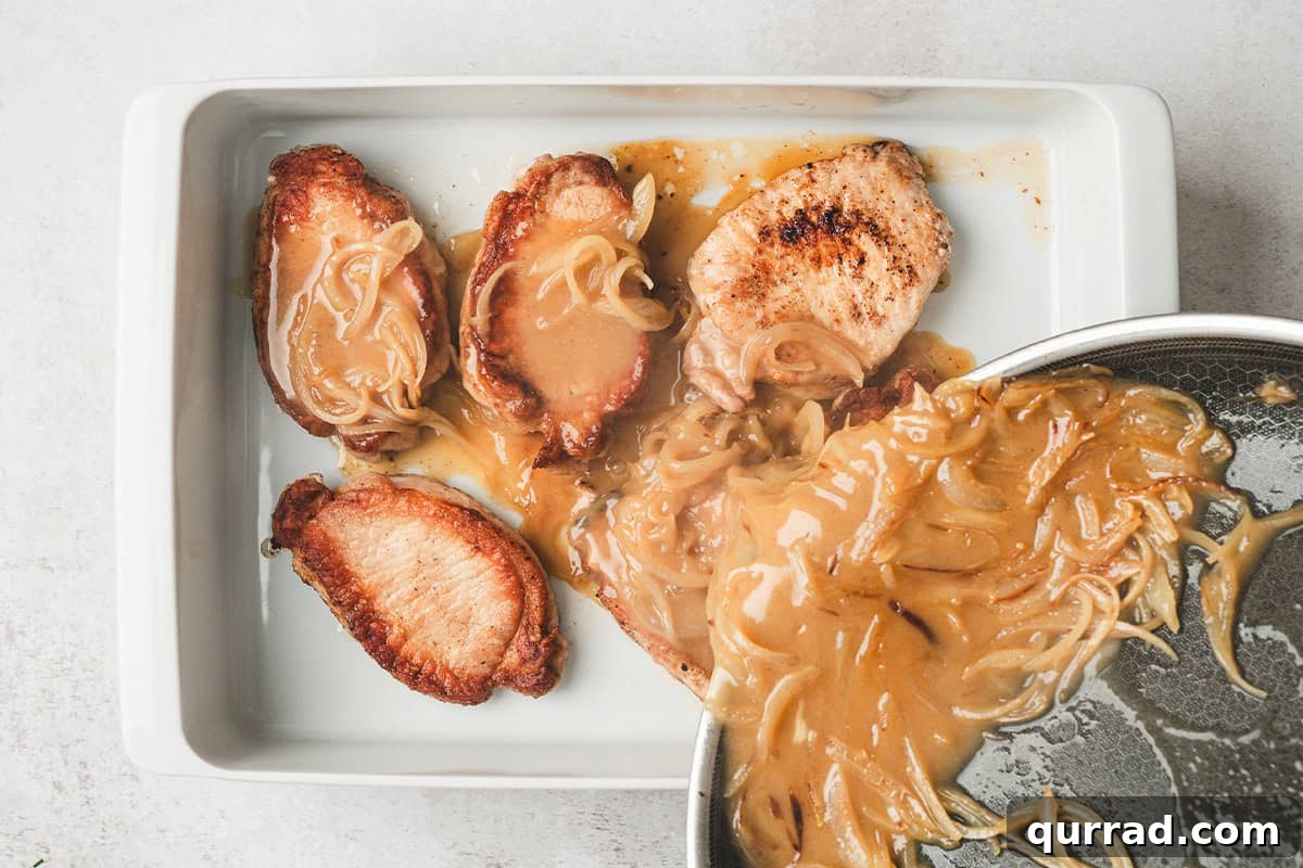 Pineapple onion sauce being poured over browned pork chops in a baking dish.