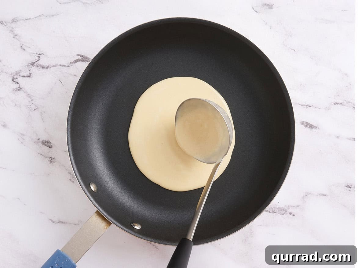 How to Make a Classic French Crepe Cake (Mille Crêpes) 9 A ladle pouring crepe batter into the center of a non-stick skillet over medium heat.