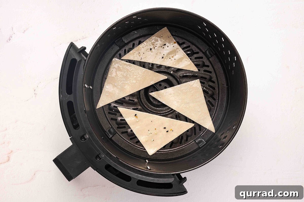 Wonton wrapper halves in an air fryer basket.