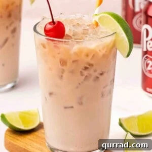 Front view of a glass of dirty soda with a lime wedge and cherry.