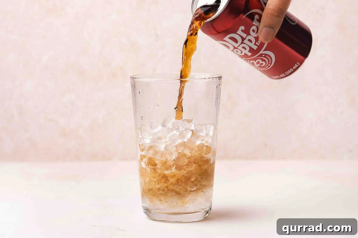 Dr pepper being poured into a glass of ice.
