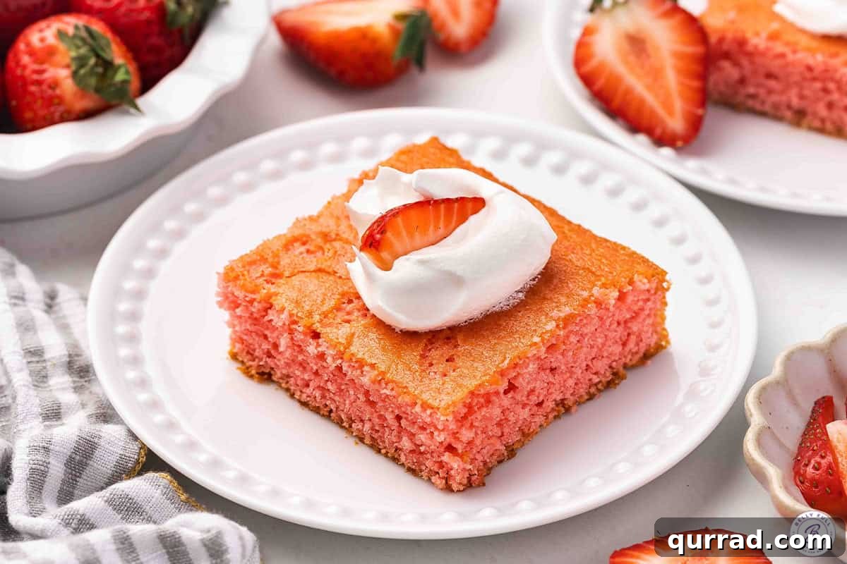 Moist Soda Cake Recipe with Creamy Vanilla Frosting 8 A slice of strawberry soda cake on a plate topped with Cool whip and a strawberry.