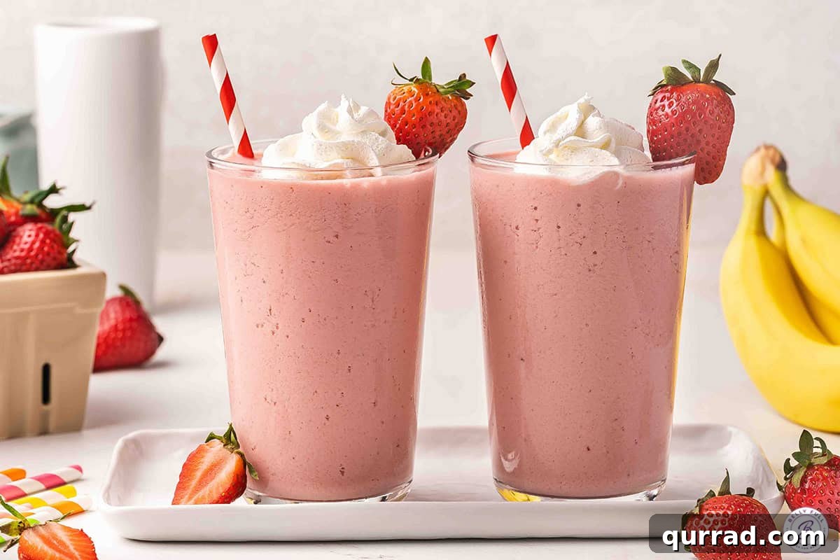 Creamy Strawberry Banana Orange Julius Smoothie 7 Two strawberry banana orange Julius drinks topped with whipped cream and a strawberry.